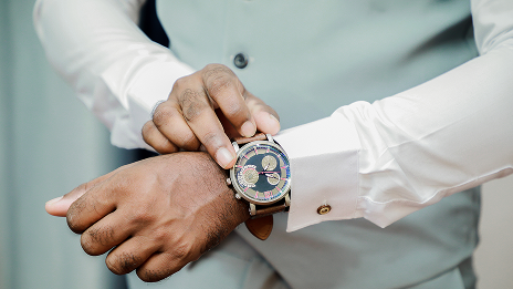 Een foto van de torso van een in man in een lichtblauw gilet gekleed, met een witte bloes en op de voorgrond zijn arm met horloge van Horloge.nl