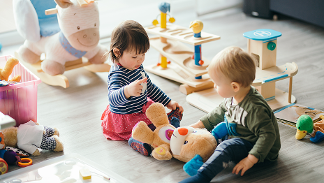 Foto van twee kindjes die met speelgoed spelen.