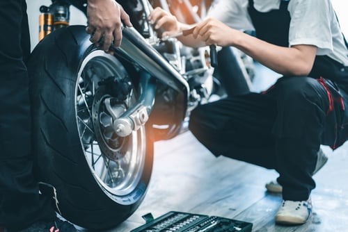 Fietsreparatie. Jonge man repareren motorfiets in garage.mechanic vaststelling motorfiets motor.Serious jonge man repareren van zijn motorfiets in fiets reparatiewerkplaats.
